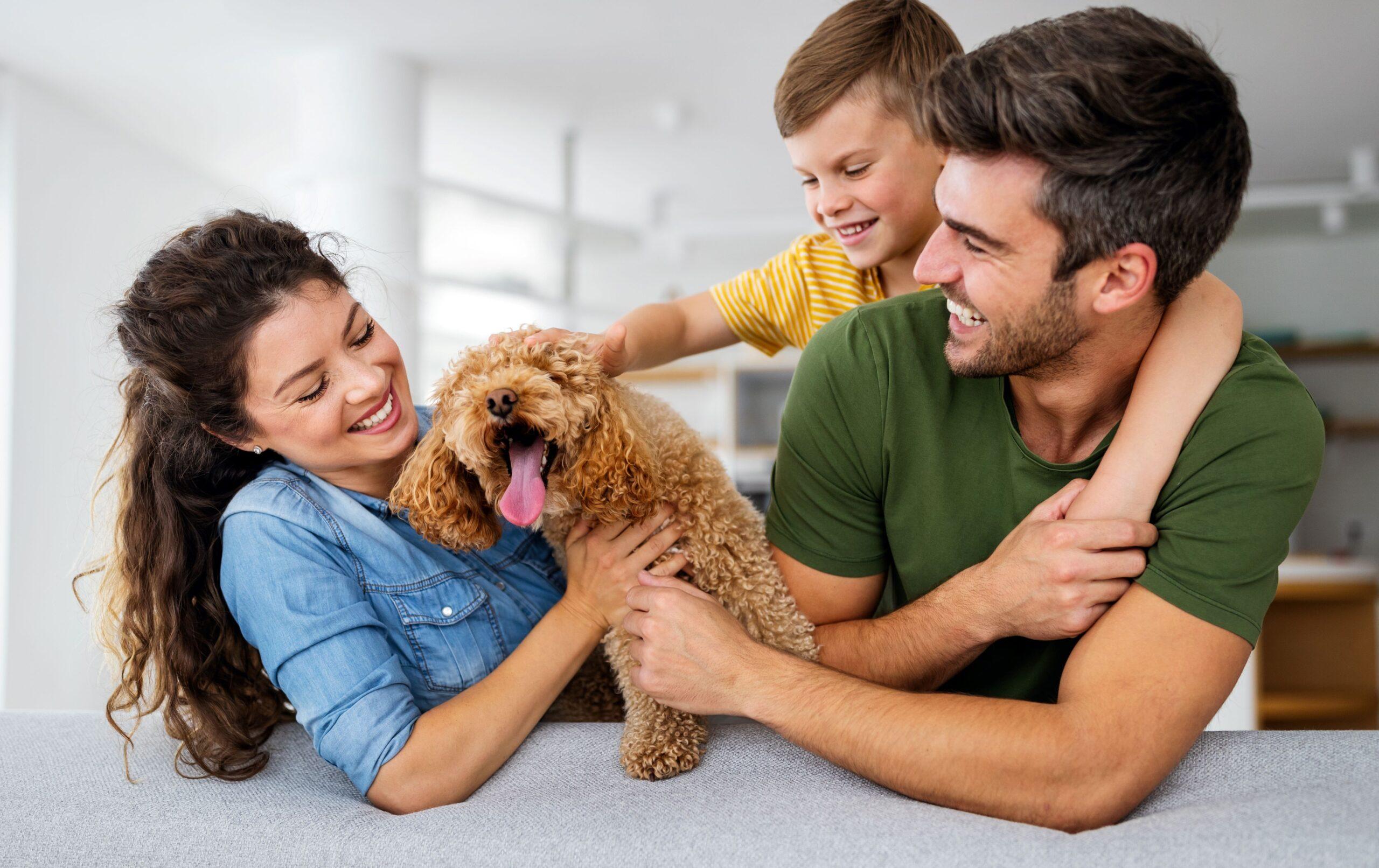 Eine lachende Familie, die einen Hund streichelt.